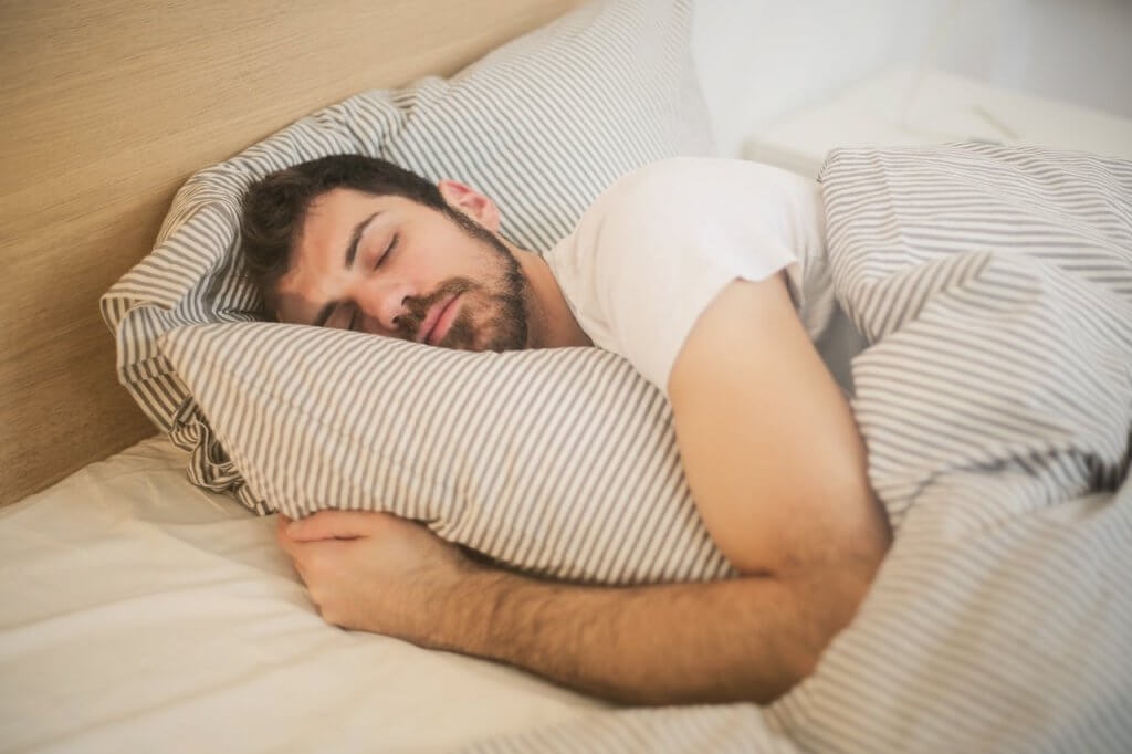 Schlafen und Lauftraining Schlafender Mann im Bett zur Regeneration nach dem Lauftraining