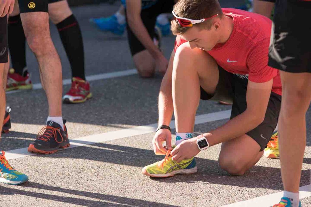 Gut vorbereitet an die Startlinie dank richtigem Tapering Läufer bindet vor dem Wettkampf die Laufschuhe