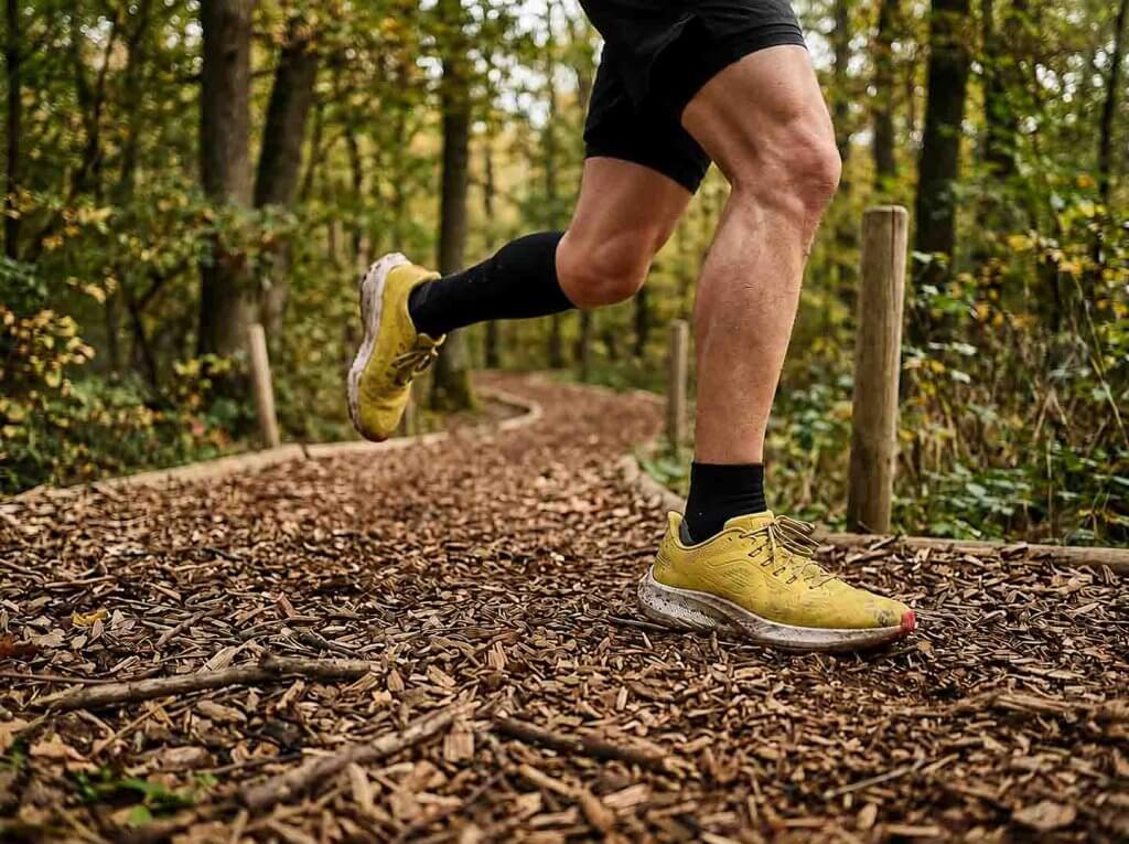 Belastung beim Joggen langsam steigern Beine eines Läufers beim Joggen auf einem unebenen Waldweg