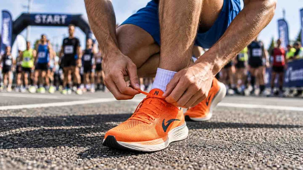 Laufschuhe richtig schnüren und Blasen vermeiden Läufer schnürt Laufschuhe vor einem Wettkampf
