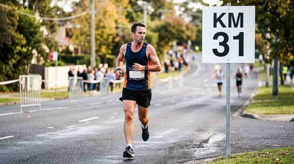 Läufer konzentriert sich beim Marathon auf das Kilometerschild 31