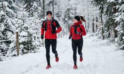 Läufer und Läuferin trainieren im Winter bei Schneefall