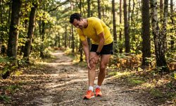 Läufer mit Muskelzerrung auf einem Waldweg