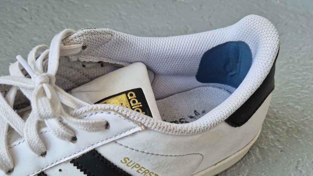 Fersenkappe reparieren – eingeklebtes Flickmaterial in einem Sneaker Sneaker mit eingeklebtem Flickmaterial zur Reparatur einer durchgescheuerten Fersenkappe
