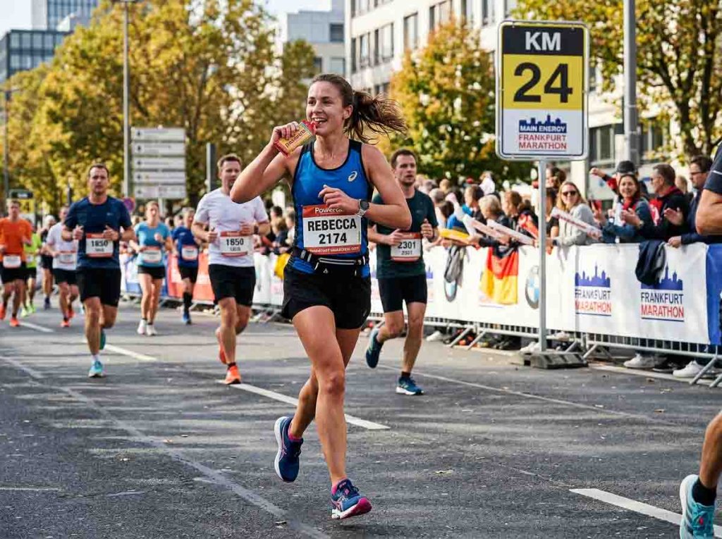 Verpflegung mit Energiegel während des Marathons Marathonläuferin nimmt bei Kilometer 24 ein Energiegel zu sich